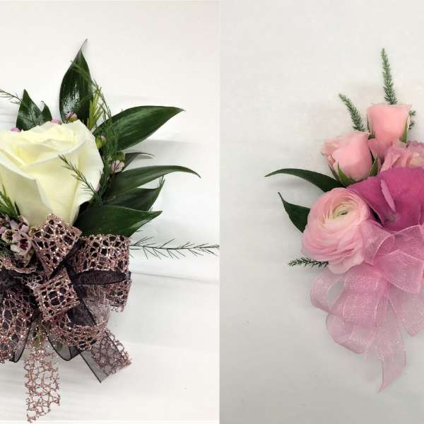 Two corsages with white and pink roses accented with decorative ribbons