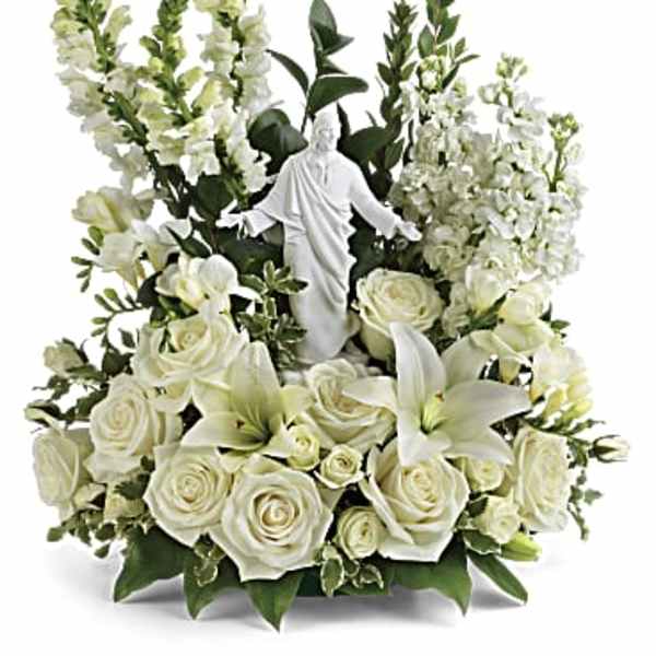 White floral arrangement with a small religious statue in the center