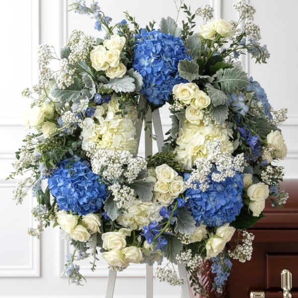 Blue and white floral funeral wreath on an easel