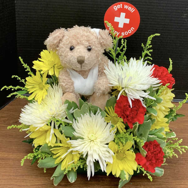 Teddy bear surrounded by yellow, white, and red flowers with a get well sign