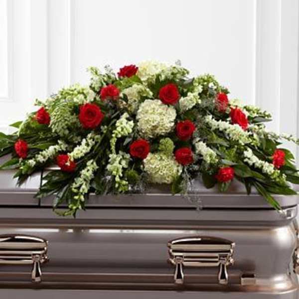 Red roses and white flowers arranged on a silver casket