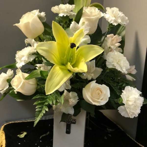 White roses and a yellow lily in a vase arrangement