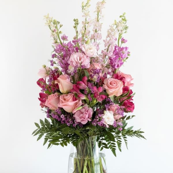 Pink and purple mixed flower arrangement in a clear glass vase