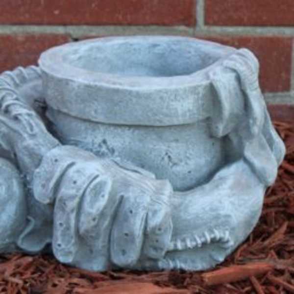 Stone garden sculpture of a baseball glove, ball, and cap
