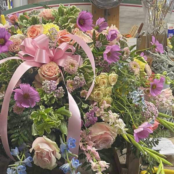 Large pink and purple floral arrangement with a pink ribbon bow