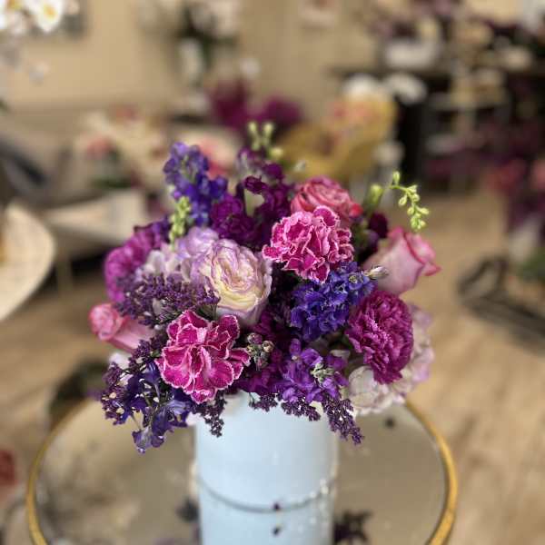Purple and pink bouquet in a light blue vase