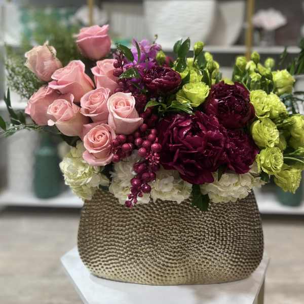 Pink roses and magenta flowers in a textured gold vase