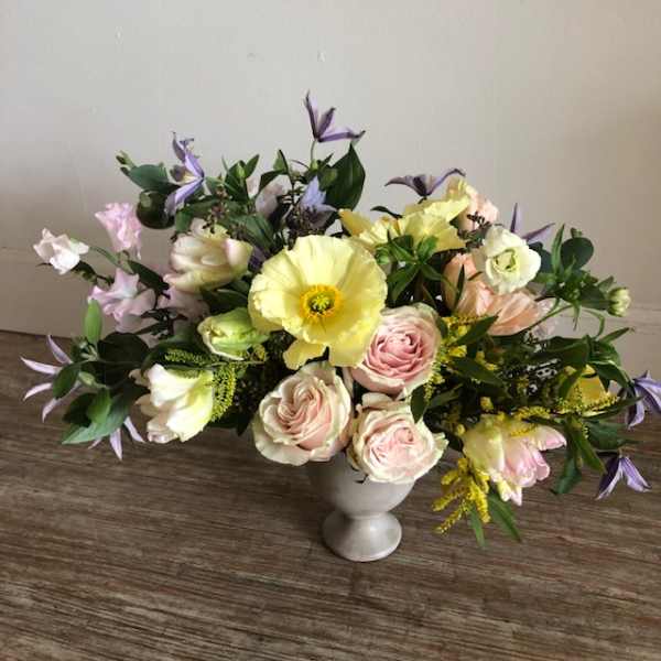 Pastel floral arrangement in a white vase with pink and yellow blooms