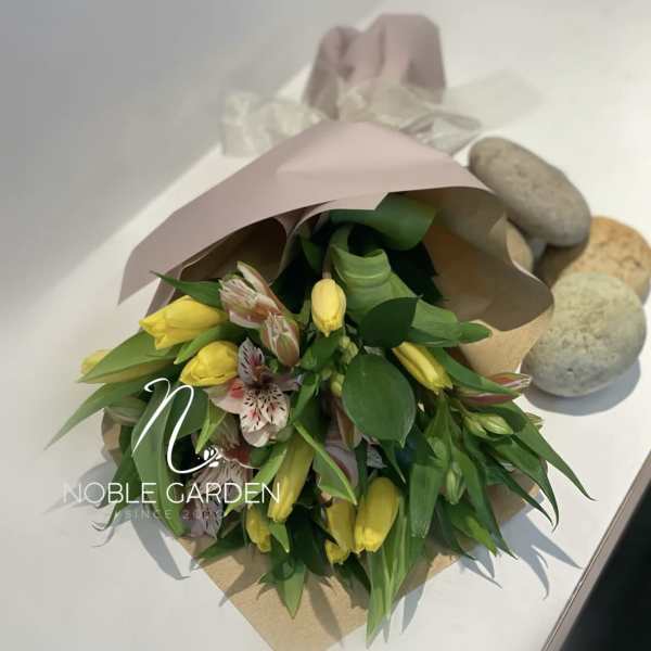 Bouquet of yellow tulips and pink alstroemeria wrapped in paper