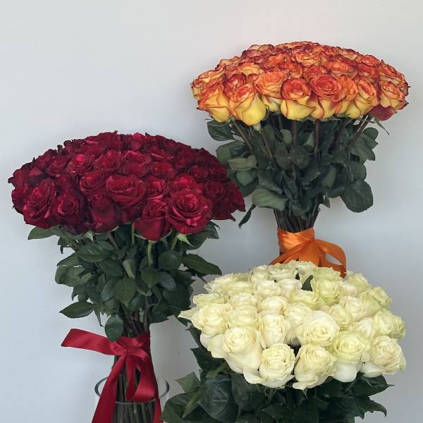 Three large rose bouquets in glass vases, in red, orange-yellow, and white