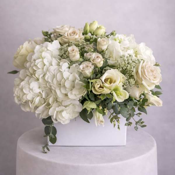 White floral arrangement with roses and hydrangeas in a white box