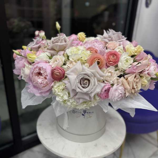 Pastel bouquet of roses, peonies, and ranunculus in a white hat box