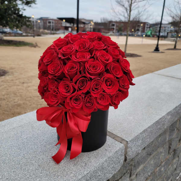 Round bouquet of red roses in a black box with a red ribbon