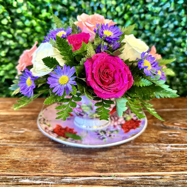 Bouquet of pink and white roses with purple daisy-like flowers in a floral teacup