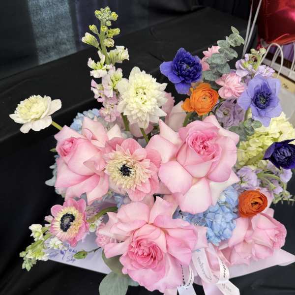 Pink roses with blue hydrangea and mixed blooms in a wrapped bouquet