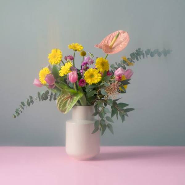 Mixed bouquet of yellow and pink flowers in a white vase