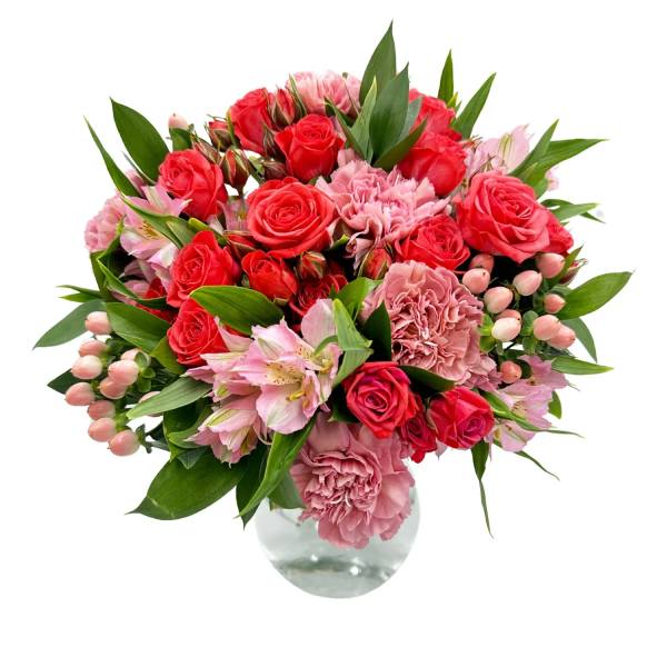 Bouquet of red roses and pink carnations in a clear glass vase