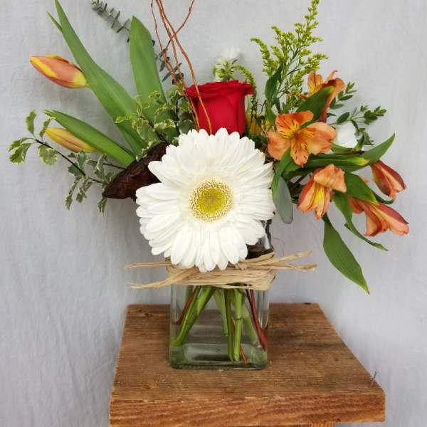 Mixed bouquet in a glass vase with a red rose, white gerbera, and orange lilies
