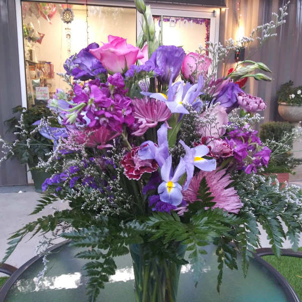 Tall bouquet of purple and pink flowers in a glass vase
