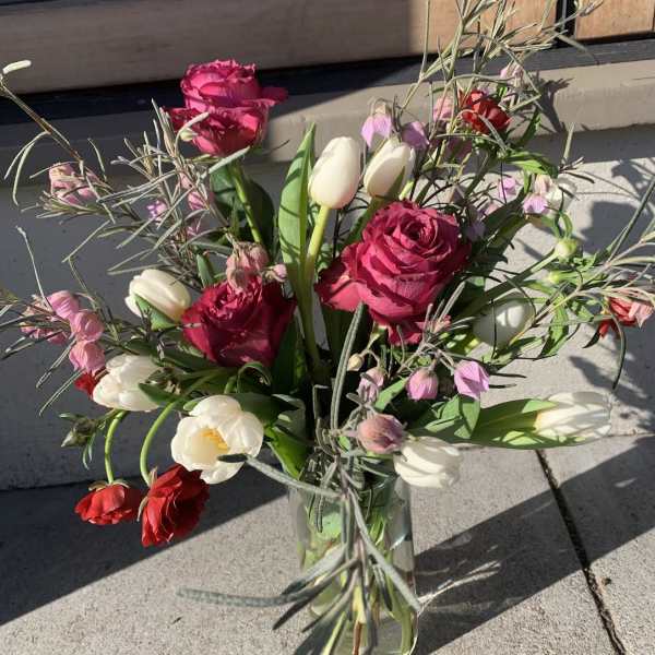Mixed bouquet of pink roses and white tulips in a glass vase