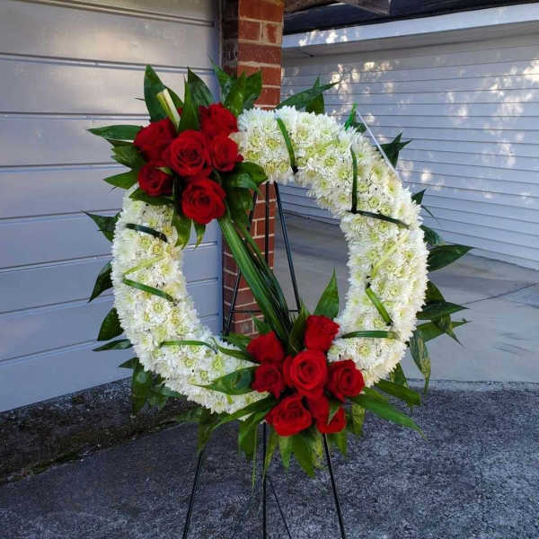 Heart-shaped floral wreath with red roses and white chrysanthemums on a stand
