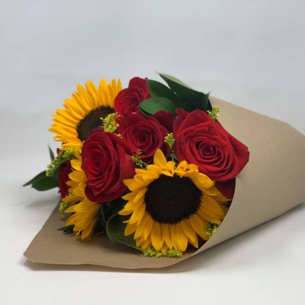 Bouquet of red roses and yellow sunflowers wrapped in brown paper