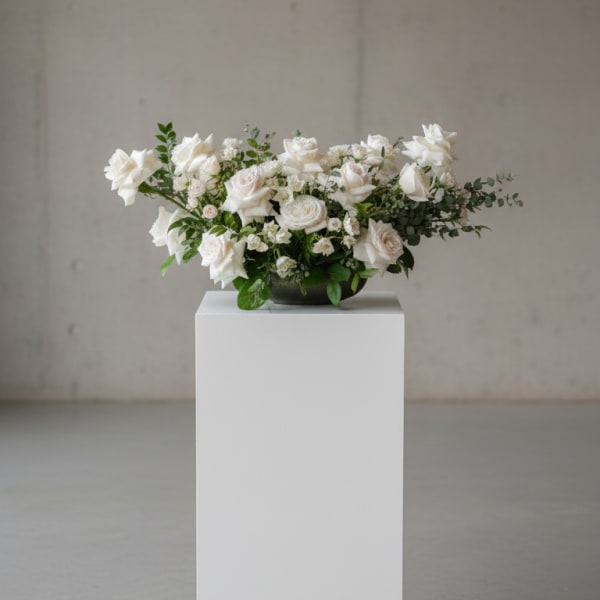 White rose arrangement in a low dark bowl on a pedestal