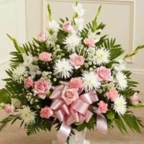 Pink roses and white spider mums in a standing arrangement with a pink ribbon