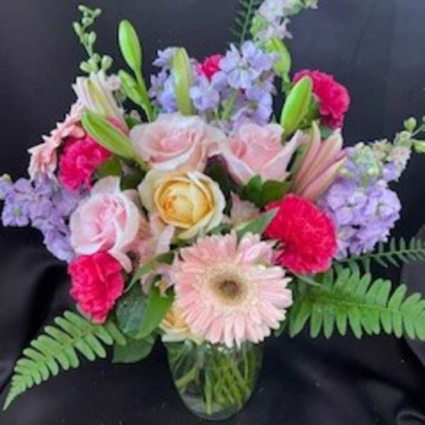 Mixed bouquet of pink, lavender, and yellow flowers in a glass vase