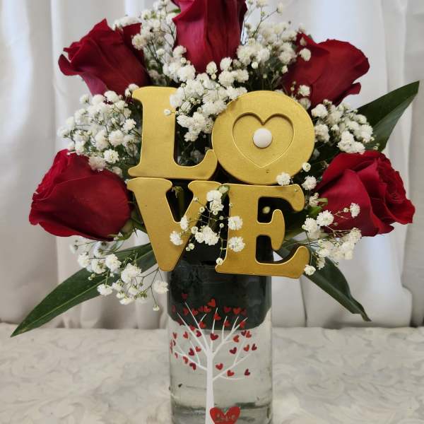 Red roses with baby's breath and a gold LOVE sign in a glass vase
