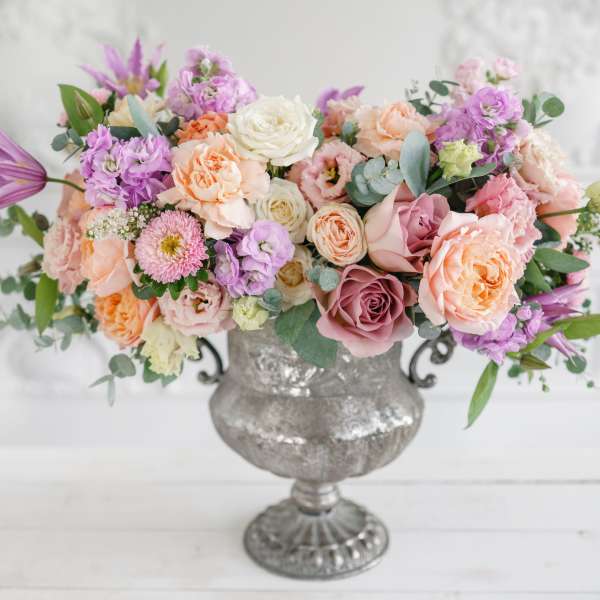 Pastel bouquet of roses and mixed blooms in a silver urn vase
