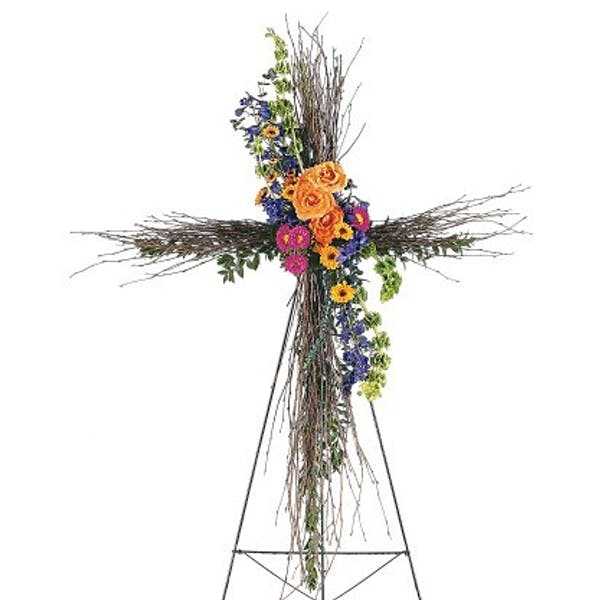 Floral cross arrangement with orange, purple, and pink flowers on a stand