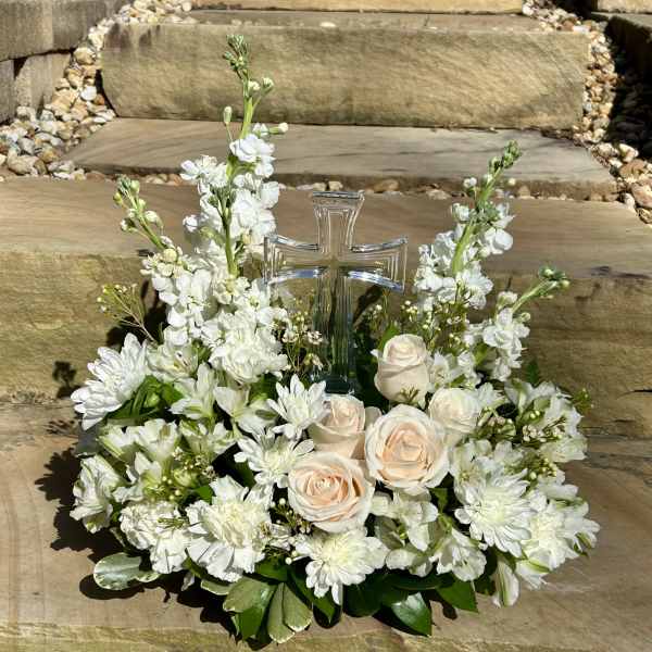 White floral arrangement with roses and a clear glass cross centerpiece
