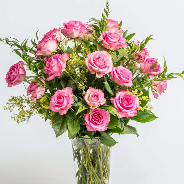 Pink roses in a clear glass vase with green filler