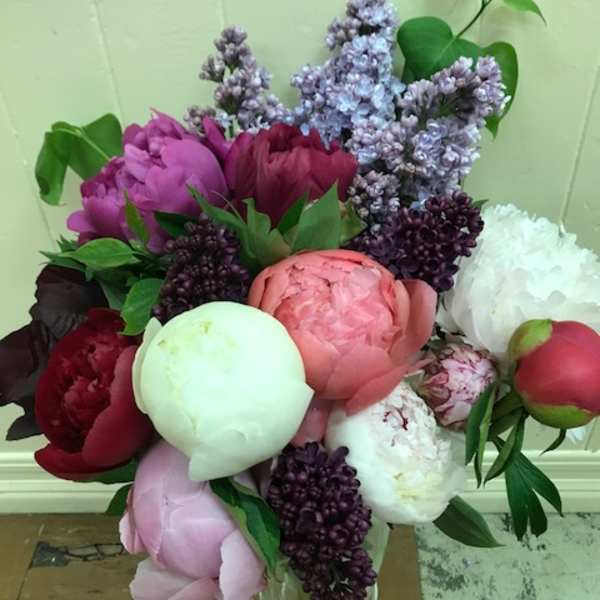 Bouquet of peonies and lilacs in a clear glass vase