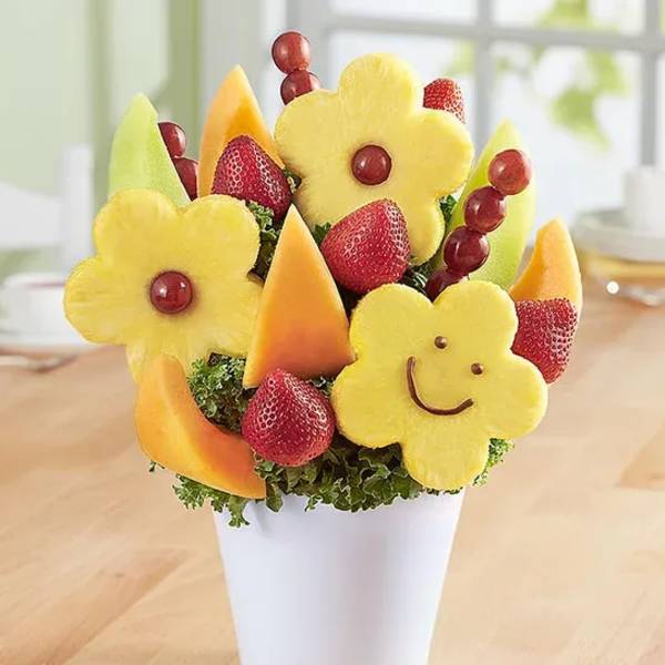 Fruit bouquet in a white cup with carved pineapple flowers and strawberries
