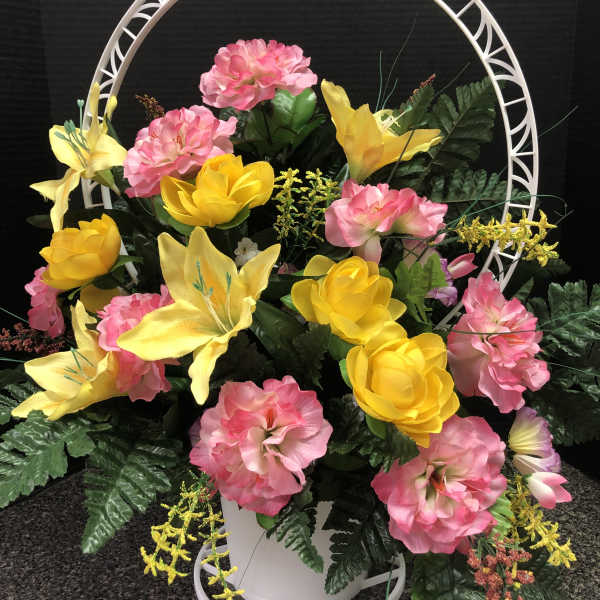 Pink and yellow floral arrangement in a white basket with a circular frame