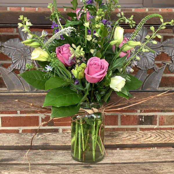 Pink roses and white blooms arranged in a glass vase