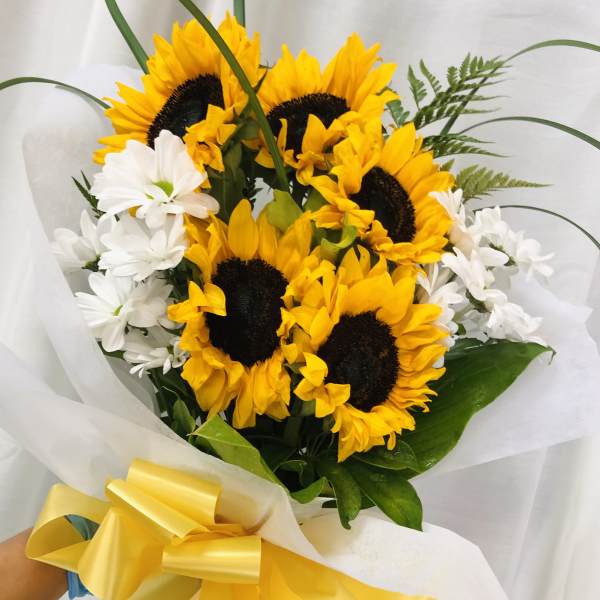 Bouquet of yellow sunflowers and white daisies wrapped with a yellow ribbon
