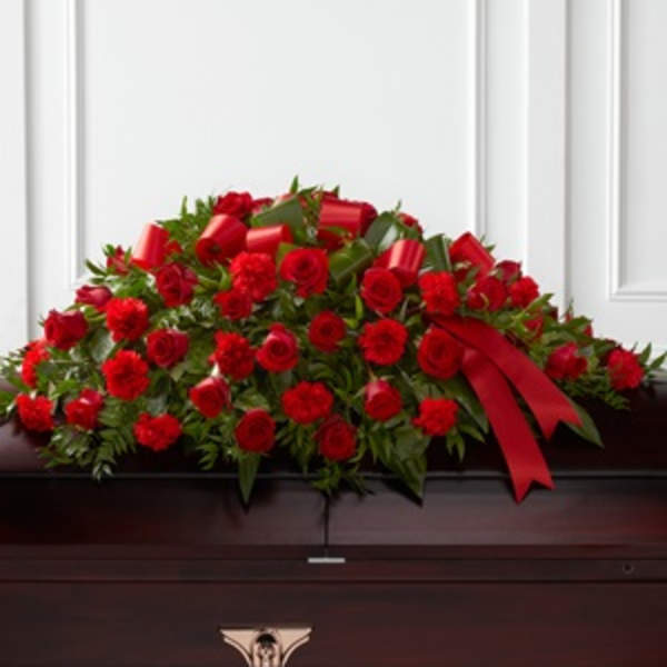 Red rose casket spray with ribbon on a dark casket