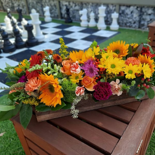 Colorful mixed flower arrangement in a wooden box on a table
