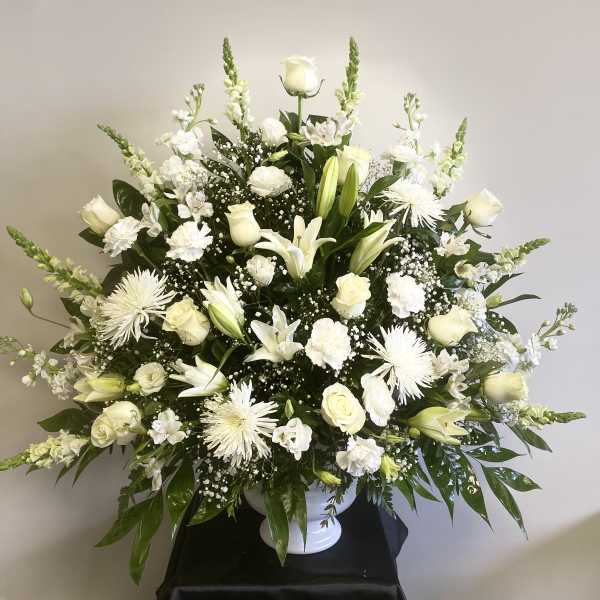 White floral arrangement in a white pedestal vase