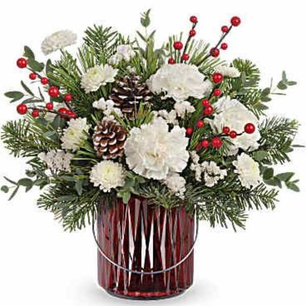 White carnations and pine in a red glass vase with red berry accents