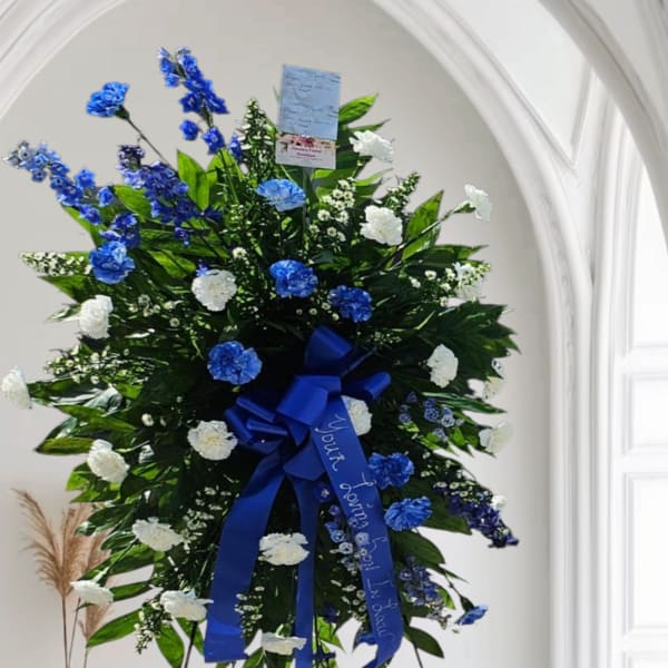 Large standing floral spray with blue and white flowers on an easel