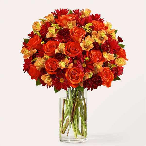 Orange and red flower bouquet in a clear glass vase