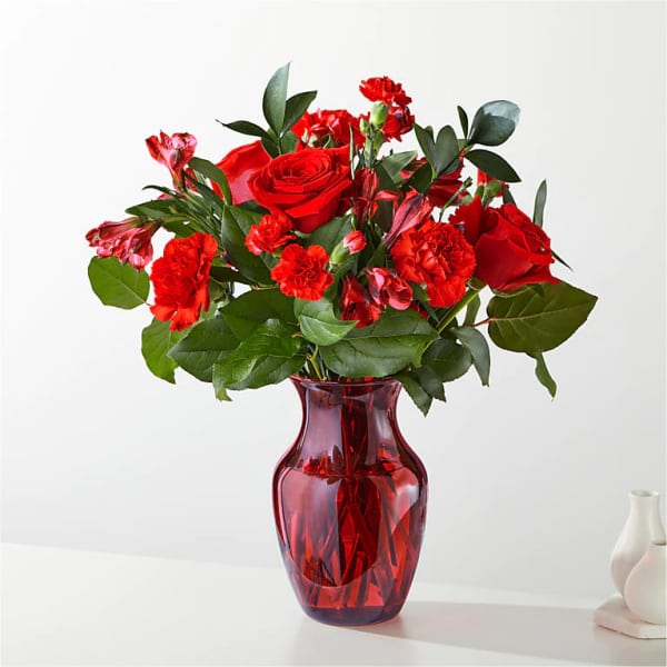 Red roses and carnations in a red glass vase