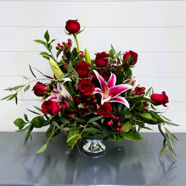 Red roses and pink lilies arranged in a silver vase