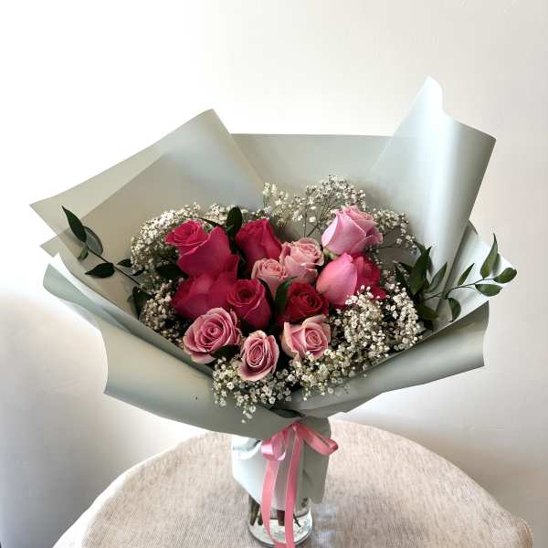 Bouquet of pink roses with baby's breath in pale wrapping