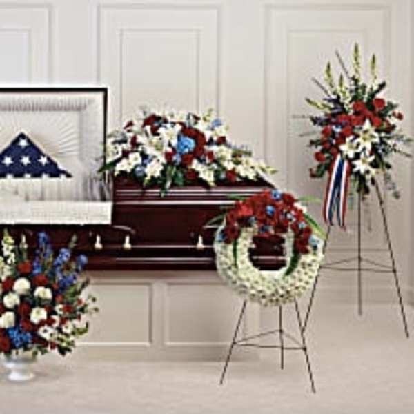 Patriotic funeral floral set with red, white, and blue arrangements around a casket
