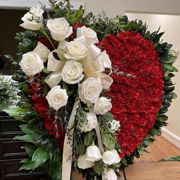 Heart-shaped red floral wreath with white roses and ribbon